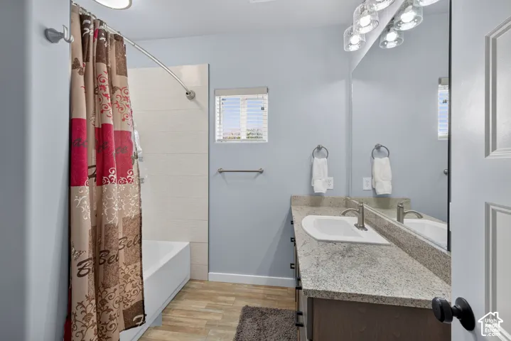 Recessed lighting, wood-finish flooring, white paneled door, and a vanity with an integrated sink and brushed nickel faucet