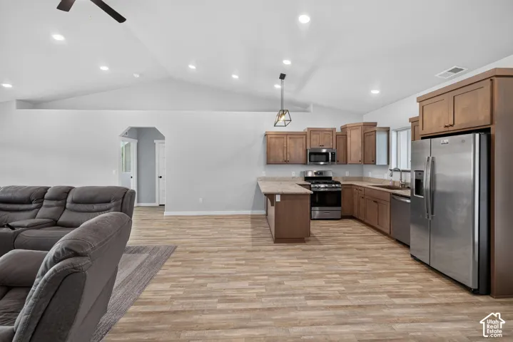 Vaulted ceilings with recessed lighting, wood-finish flooring, stainless steel appliances, wood cabinetry, and a kitchen island with countertop seating