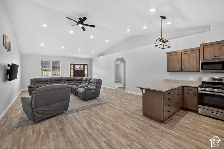 Vaulted ceilings with recessed lighting, wood-finish flooring, kitchen with built-in cabinetry, stainless steel appliances, and a central ceiling fan