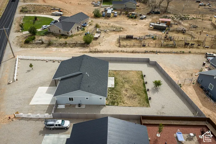 Light gray siding with a dark asphalt shingle roof, concrete driveway, fenced yard, and a small patch of grass