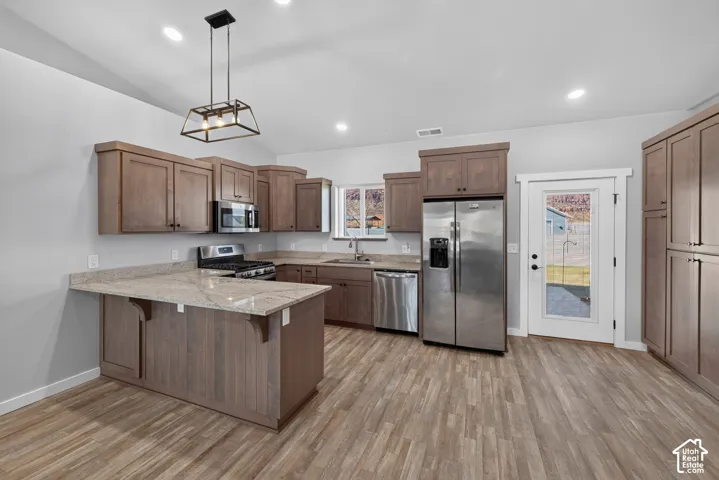 Kitchen featuring wood-finish flooring, recessed lighting, wood cabinetry, stainless steel appliances, and a kitchen island with stone countertops