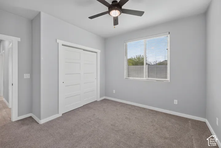 Recessed window with blinds, ceiling fan with integrated lighting, wall-to-wall carpeting, and bright white trim