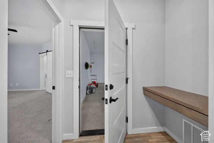 Built-in wood-finish desk, wood-finish flooring, white paneled doors, and barn door hardware