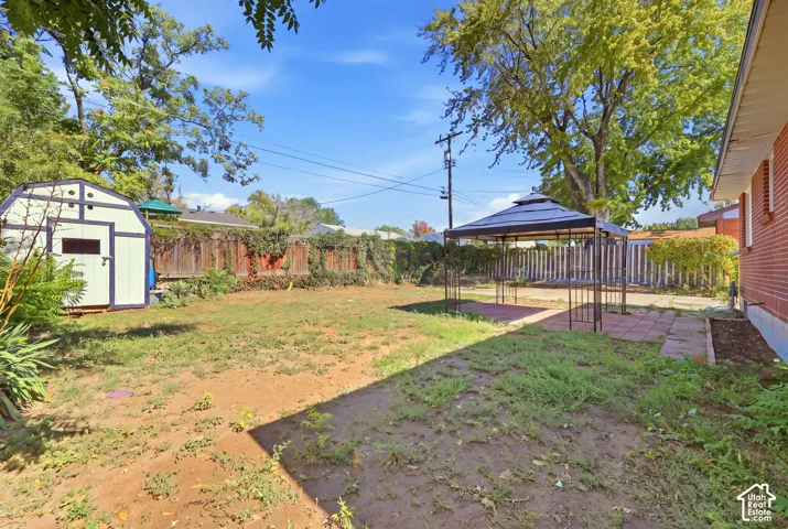 Spacious backyard featuring a storage shed, brick exterior, and a paved patio area
