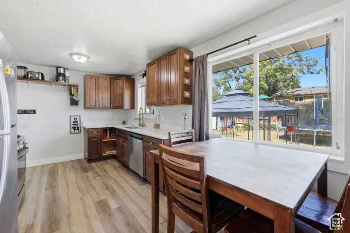 Kitchen featuring wood-finish flooring, wood cabinetry, white countertops, and stainless steel appliances