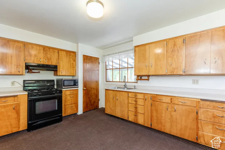 Extensive wood-finish cabinetry, solid surface countertops, and a stainless steel sink with a window above