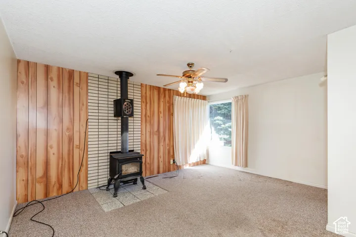 Wood-paneled accent wall with a cast iron wood-burning stove on a tiled hearth