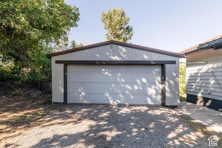 Detached garage with a pitched roof, vertical panel siding, and a paneled garage door