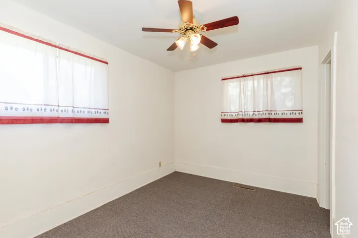 Carpeted flooring with white wall finishes, equipped with a ceiling fan and overhead lighting