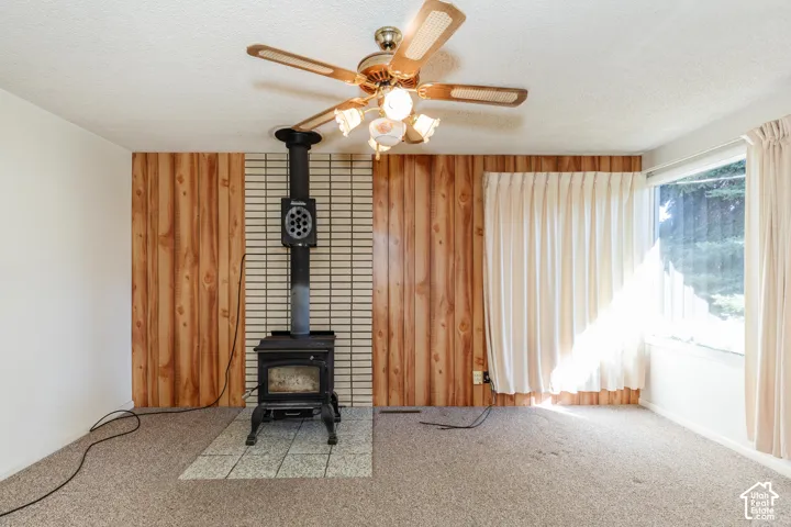 Cast iron wood-burning stove with a tiled hearth and a wood-paneled accent wall