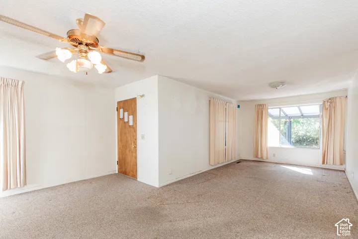 Recessed ceiling light, ceiling fan with integrated lighting, wood-paneled door, large window, and carpeted flooring
