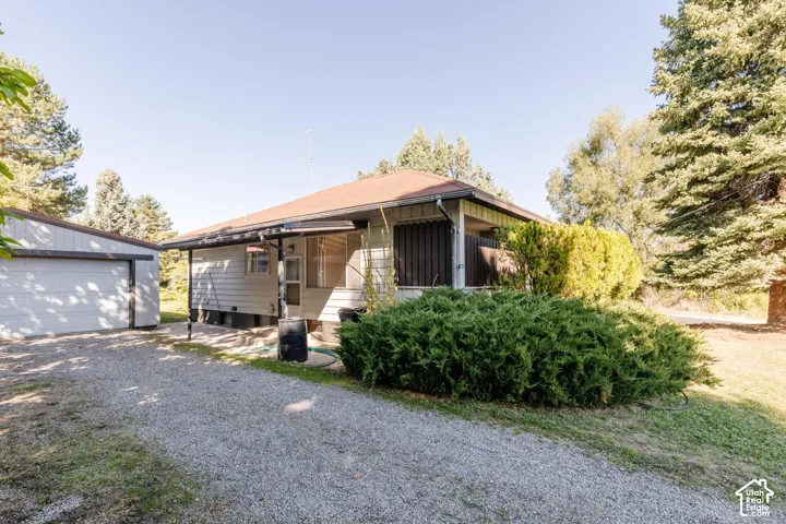 Ranch-style residence featuring a covered porch entrance and a detached garage with a gravel driveway
