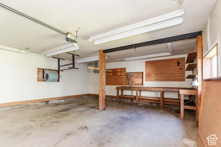 Concrete flooring garage with exposed wood support beams and built-in wood shelving