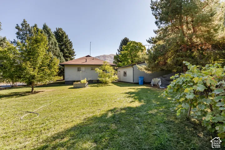 Expansive lawn surrounding the property, mature trees providing shade, and a separate outbuilding