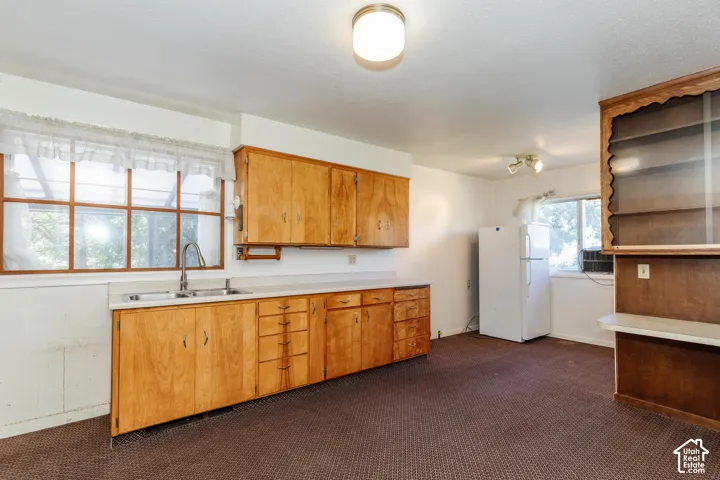 Wood-finish cabinetry, white countertops, stainless steel sink, track lighting, and a built-in display cabinet