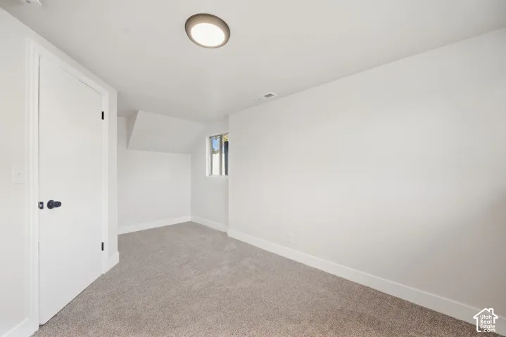 Recessed ceiling light, white walls, white trim, light-colored carpet, and a window