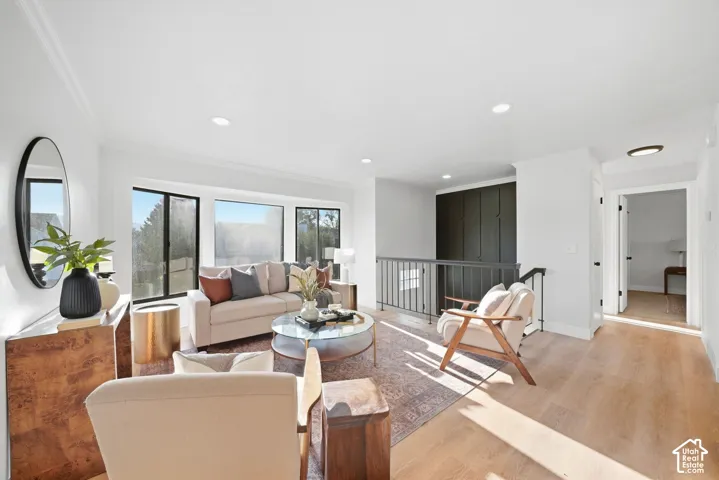 Bright living area featuring large picture windows, wood-finish flooring, recessed lighting, and a dark built-in wall unit