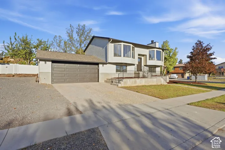 Split-level residence featuring gray siding and a brown garage door