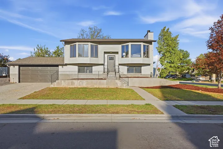Split-level residence featuring a two-car garage, bay windows, and a concrete driveway