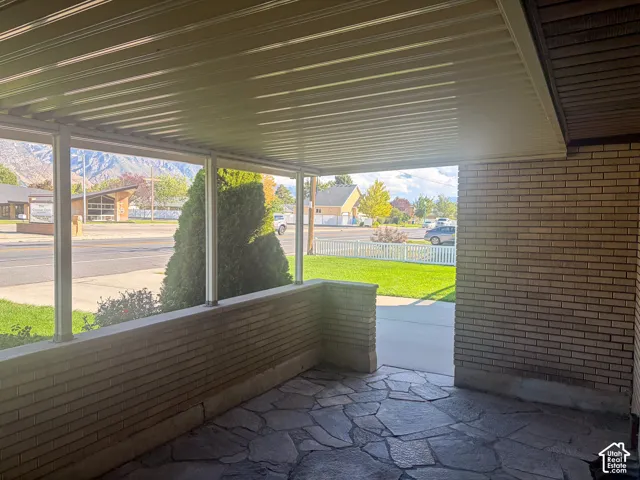 Covered patio with flagstones, brick knee wall, and a slatted ceiling