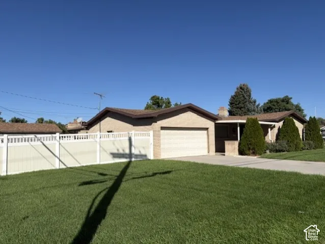 Brick exterior with attached garage, concrete driveway, and a white privacy fence (fully enclosed backyard)