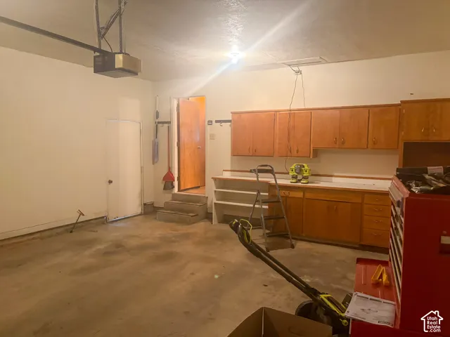 Attached garage with concrete flooring, built-in wooden cabinetry, and a work surface