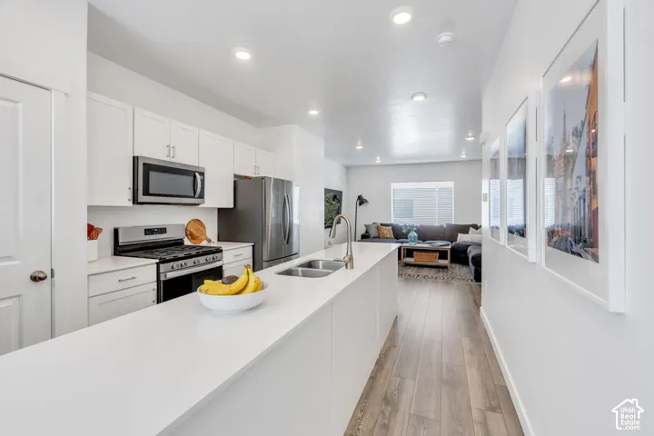 Kitchen featuring white cabinetry, stainless steel appliances, wood-finish flooring, recessed lighting, and a white countertop