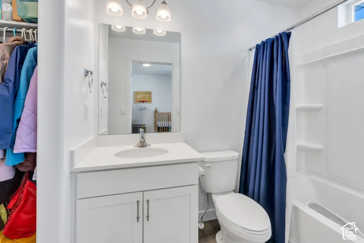 White vanity with integrated sink, chrome faucet, wall-mounted mirror, and overhead lighting
