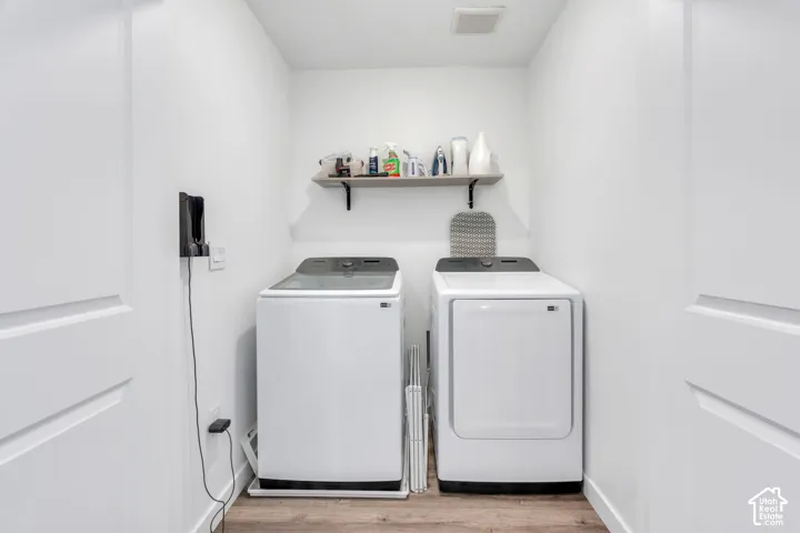 Laundry area featuring a wood-finish flooring and a wall-mounted shelf