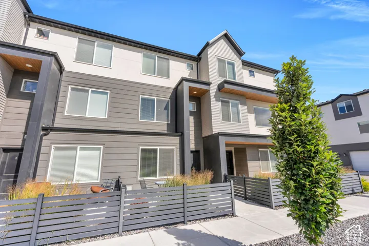Contemporary multi-level exterior with mixed siding, multiple windows, and a private fenced patio area