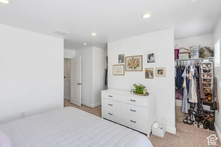 Recessed lighting, neutral carpeting, and a built-in closet with shelving
