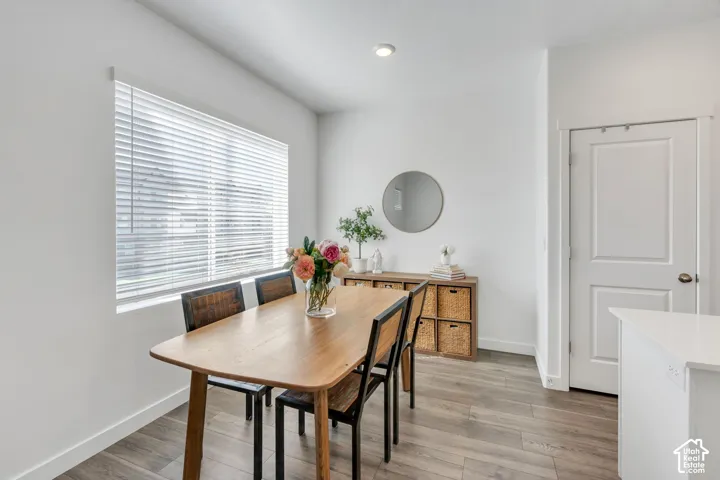 Recessed lighting, wood-finish flooring, white horizontal blinds, white paneled door, and white countertops