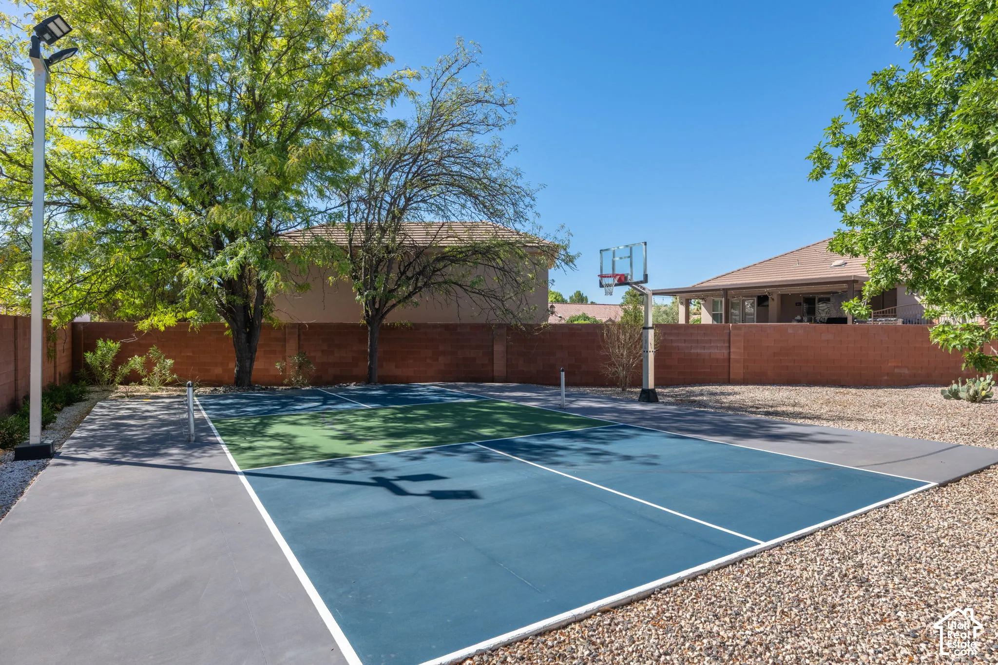 Outdoor sports court with painted surface, integrated basketball hoop, and a net pole