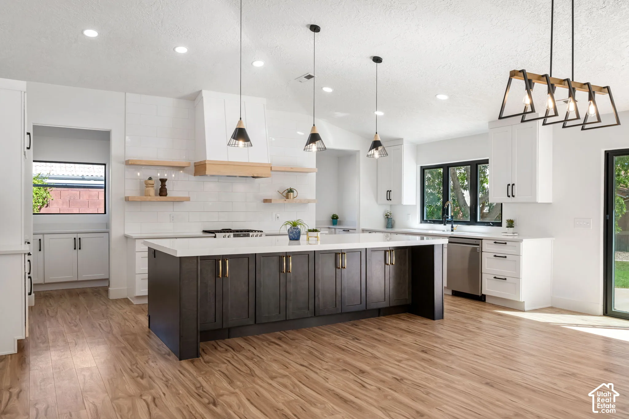 Open-concept kitchen featuring an oversized island with dark wood-finish cabinetry, white countertops, and wood-finish flooring