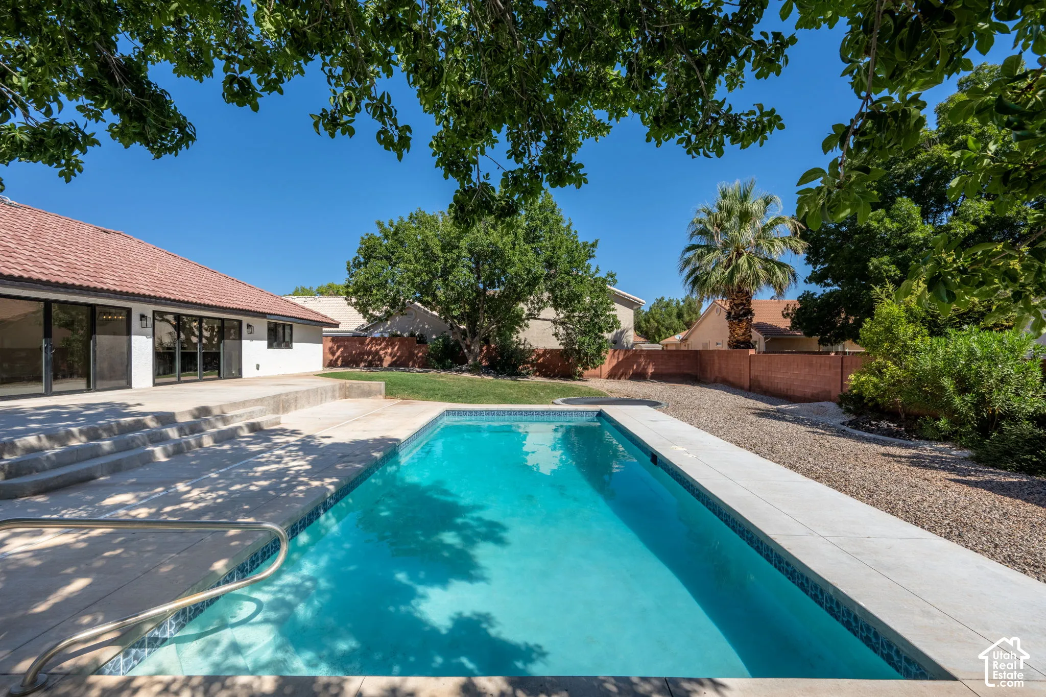 Backyard featuring a rectangular swimming pool, expansive concrete patio, and a tiled roofline