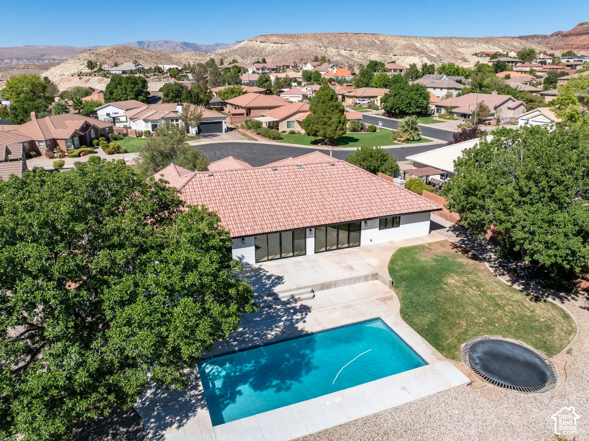 Property featuring a red tile roof, white exterior, multiple large windows, and a rectangular swimming pool
