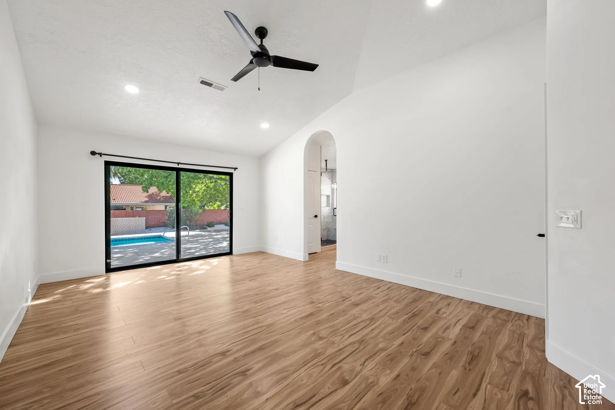 Vaulted ceiling with a ceiling fan, wood-finish flooring, recessed lighting, and sliding glass doors to the outdoor pool