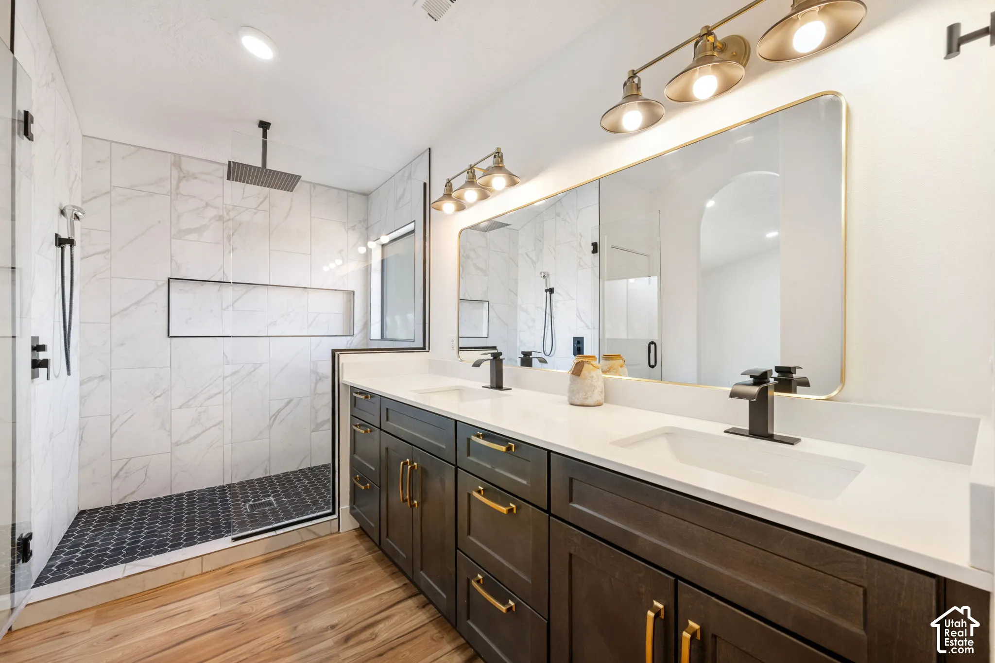 Dual vanity with dark wood-finish cabinetry, gold-tone hardware, and white countertops