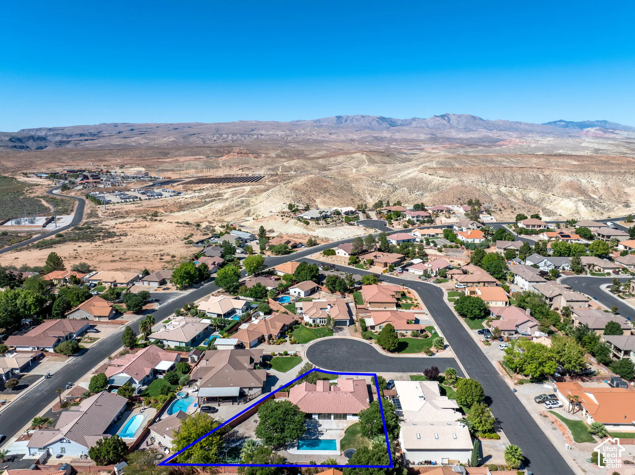 Aerial perspective highlighting the property outlined in blue, featuring a private swimming pool, mature trees, and a red tile roof