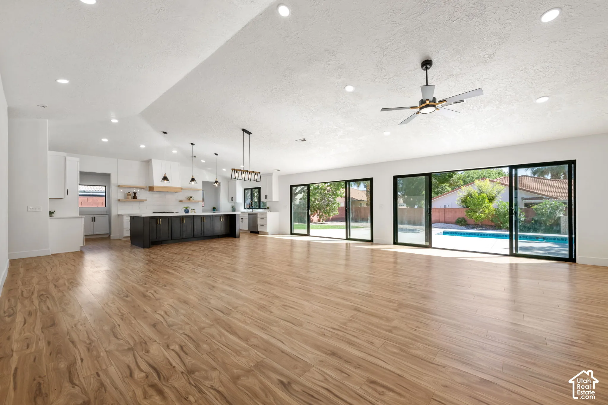 Expansive open-concept living area with wood-finish flooring, recessed lighting, and a contemporary ceiling fan