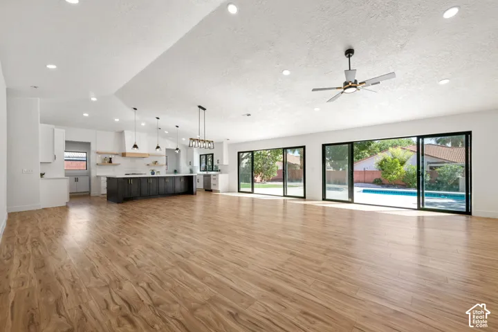 Expansive open-concept living area with wood-finish flooring, recessed lighting, and a contemporary ceiling fan