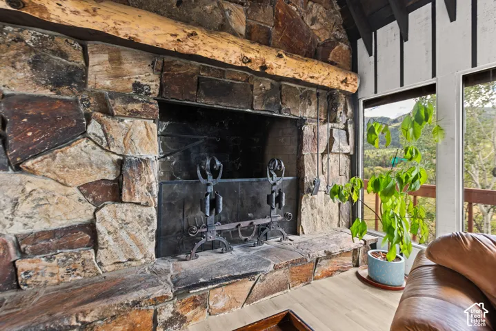 Stone-clad fireplace with a wood mantel, integrated hearth, and a metal fire screen