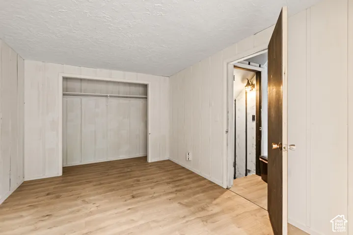 Wood-finish flooring, white panel walls, and an open closet with hanging rod