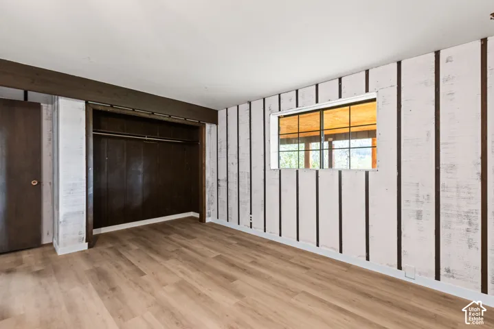 Wood-finish flooring with white paneled walls and a built-in closet with a hanging rod