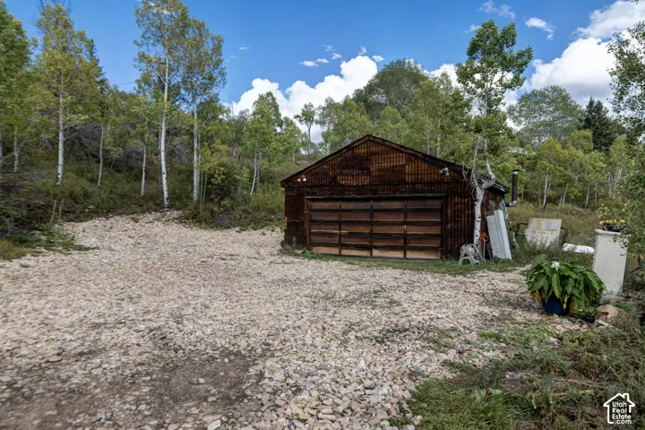 Gravel parking area featuring a detached wood-sided garage with a large garage door