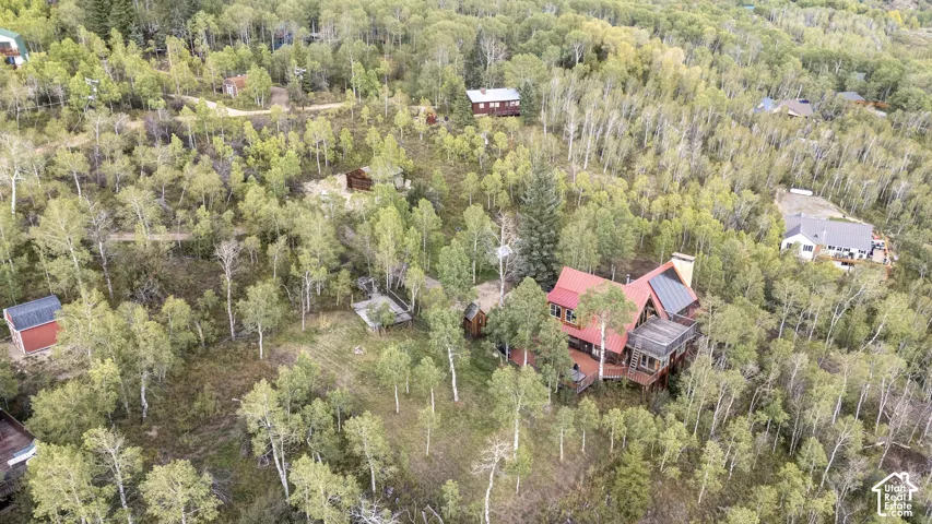 Property situated among abundant mature trees, featuring a multi-level deck and a red-toned roof