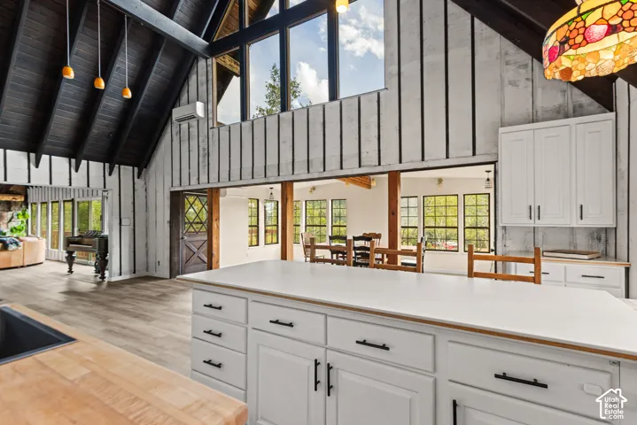 Vaulted wood-paneled ceiling, expansive windows, kitchen island with built-in storage, wood-finish flooring, and a unique diamond-pattern wooden door