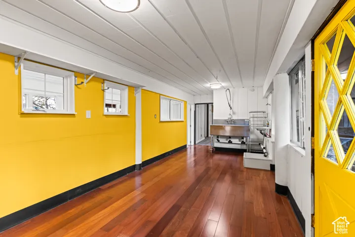Hardwood flooring, paneled ceiling, multiple windows, built-in stainless steel utility sink, and a multi-pane door