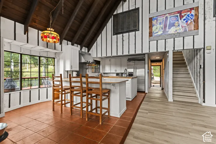 Vaulted wood-plank ceiling, kitchen island with wood countertop, stainless steel appliances, grid-pattern windows, and wood-finish flooring
