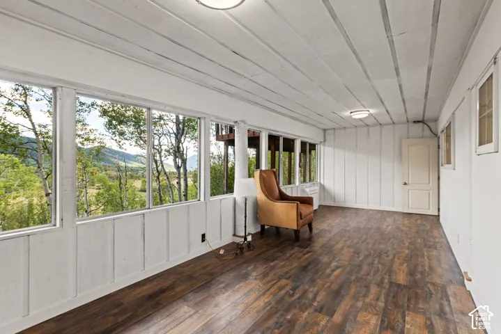 Wood-finish flooring, white paneling, and a white plank ceiling with flush-mount lighting